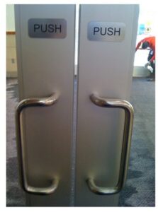 Double doors with protruding handles and signs that read push.